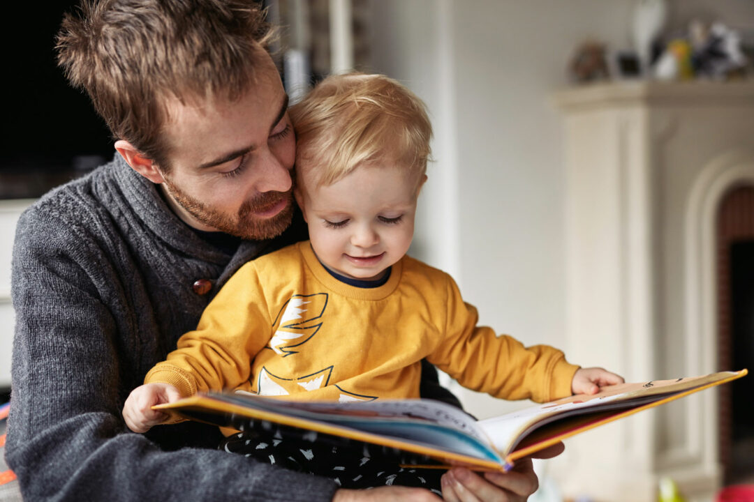 Father looking at picture book with young son